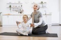 Loving mommy gently stretching daughter& x27;s arms during fitness class at home. Royalty Free Stock Photo
