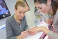 Attractive nail salon worker giving manicure regular customer