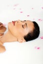 Attractive naked woman lying in a milk bath. With rose petal. Up Royalty Free Stock Photo