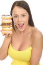 Attractive Natural Happy Young Woman Holding a Pile of Iced Donuts