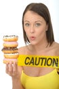 Attractive Natural Young Woman Holding a Pile of Iced Donuts with Caution Sign Royalty Free Stock Photo