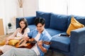 Attractive new marriage man and woman sit on the floor enjoy singing and playing guitar in the living room at the new home.