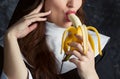 Attractive nun holding a banana and bites him on a dark background Royalty Free Stock Photo
