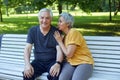 Attractive older couple talking seated on bench in summer park Royalty Free Stock Photo