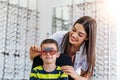 Attractive ophthalmologist examining youg boy with optometrist trial frame. Kid patient to check vision in ophthalmological clinic
