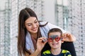 Attractive ophthalmologist examining youg boy with optometrist trial frame. Kid patient to check vision in ophthalmological clinic