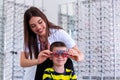 Attractive ophthalmologist examining youg boy with optometrist trial frame. Kid patient to check vision in ophthalmological clinic