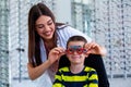 Attractive ophthalmologist examining youg boy with optometrist trial frame. Kid patient to check vision in ophthalmological clinic