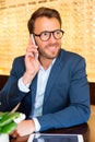 Attractive optician using mobile phone in his glasses shop