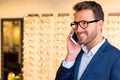 Attractive optician using mobile phone in his glasses shop