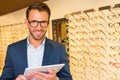 Attractive optician working with tablet in his glasses shop