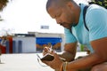 Attractive pensive African-American hipster man wearing backpack and making notes in copybook in city park. Student Royalty Free Stock Photo