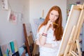 Attractive pensive female artist thinking and drawing on canvas