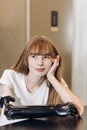 Attractive pensive girl with amputated arm sitting at the table