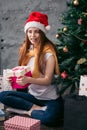 Attractive pleasant ginger girl holding a present from Santa