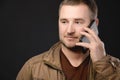 An attractive positive Caucasian man in casual clothes is talking on the cellphone and looking to the side. Studio shot Royalty Free Stock Photo