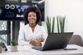 Attractive positive smiling successful young black-skinned businesswoman with afro hairstyle, posing to camera while Royalty Free Stock Photo