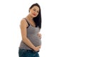 Attractive pregnant girl with dark hair touching her big belly and looking at the camera isolated on white background Royalty Free Stock Photo