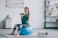 attractive pregnant woman exercising with dumbbells on fitness ball Royalty Free Stock Photo