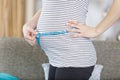 Attractive pregnant woman with measuring tape measures belly