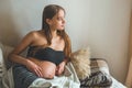 Attractive pregnant woman is sitting in bed and holding her belly. Last months of pregnancy. Royalty Free Stock Photo