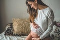 Attractive pregnant woman is sitting in bed and holding her belly. Last months of pregnancy. Royalty Free Stock Photo