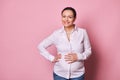 Attractive middle aged pregnant woman touching her belly, smiling looking at camera, enjoying a happy carefree pregnancy Royalty Free Stock Photo