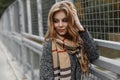 Attractive pretty cute young woman in a vintage autumn stylish coat in a fashionable beige scarf is standing outdoors