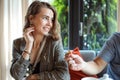 Attractive pretty shy fashionable blond curly woman smiling to cropped unrecognizable man give, regaling cookie in cafe Royalty Free Stock Photo