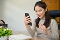 Pretty young Asian female office worker using her smartphone at her office desk Royalty Free Stock Photo