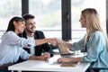 Attractive real-estate agent shaking hands with young couple after signing agreement contract in the office Royalty Free Stock Photo