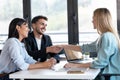 Attractive real-estate agent shaking hands with young couple after signing agreement contract in the office Royalty Free Stock Photo