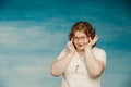 Attractive red-haired plump woman in a white suit adjusts red glasses on a blue background, Royalty Free Stock Photo