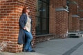 Attractive red-haired woman in a blue coat stands outside a brick building Royalty Free Stock Photo