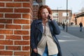 Attractive red-haired woman in a blue coat is talking on a mobile phone Royalty Free Stock Photo