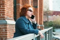 Attractive red-haired woman in a blue coat is talking on a mobile phone Royalty Free Stock Photo