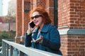 Attractive red-haired woman in a blue coat is talking on a mobile phone Royalty Free Stock Photo