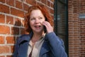 Attractive red-haired woman in a blue coat is talking on a mobile phone Royalty Free Stock Photo