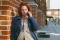 Attractive red-haired woman in a blue coat is talking on a mobile phone Royalty Free Stock Photo