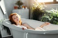 Red-haired woman relaxing in bathtub with foam in spa center.