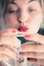 Attractive red lip stick: Blonde young woman with colorful nail polish is looking herself in the mirror. Kiss mouth