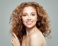 Attractive redhead girl with clear skin and long healthy curly hair. Beautiful female face on gray background