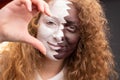Attractive redhead woman fan football Qatar face painted in national flag making half heart sign using one hand only.