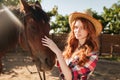 Attractive redhead young woman cowgirl in hat with her horse Royalty Free Stock Photo