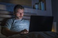 Attractive and relaxed internet addict man networking concentrated late at night on bed with laptop computer in social media Royalty Free Stock Photo