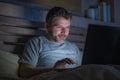 Attractive and relaxed internet addict man networking concentrated late at night on bed with laptop computer in social media Royalty Free Stock Photo