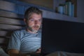 Attractive and relaxed internet addict man networking concentrated late at night on bed with laptop computer in social media Royalty Free Stock Photo