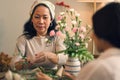 Attractive retired Asian woman enjoys arranging a vase with fresh flowers in a workshop Royalty Free Stock Photo