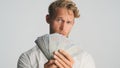 Attractive rich bearded businessman looking confident showing wad of money on camera over white background