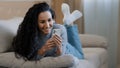 Attractive 25s girl lying on couch holding phone resting relaxing having fun chatting in internet young woman smiling Royalty Free Stock Photo